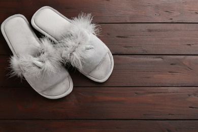 Photo of Pair of stylish soft slippers on wooden background, flat lay. Space for text