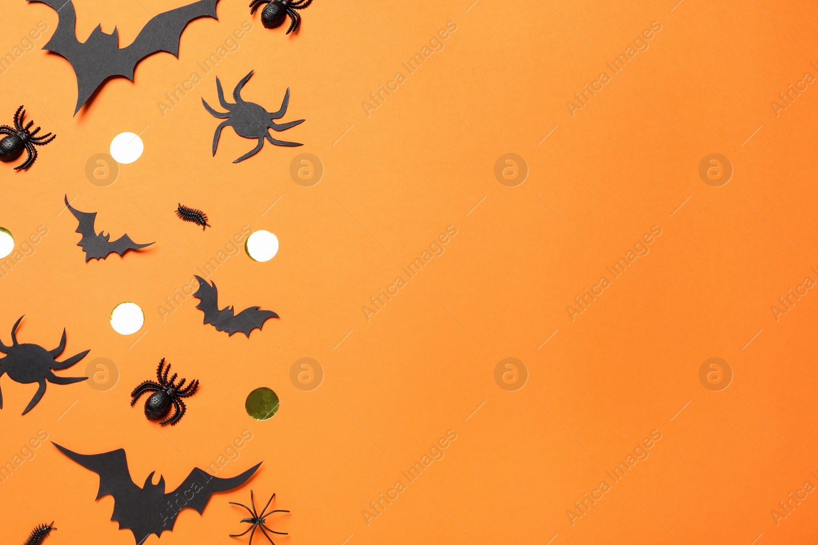 Photo of Flat lay composition with paper bats and spiders on orange background, space for text. Halloween decor