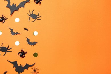 Flat lay composition with paper bats and spiders on orange background, space for text. Halloween decor
