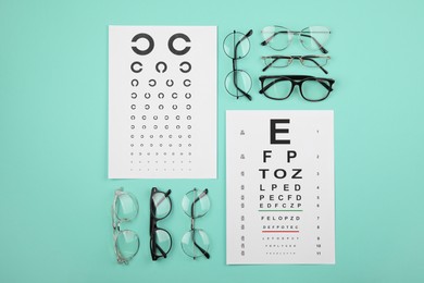Vision test chart and glasses on turquoise background, flat lay