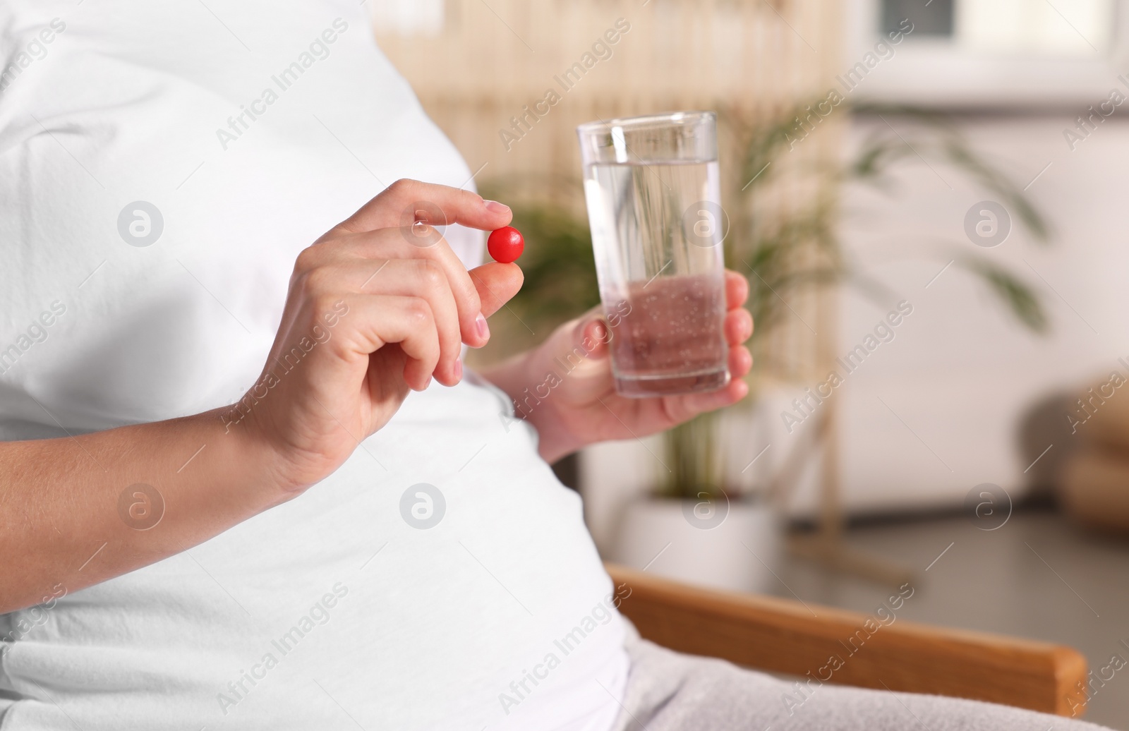 Photo of Pregnant woman taking pill at home, closeup