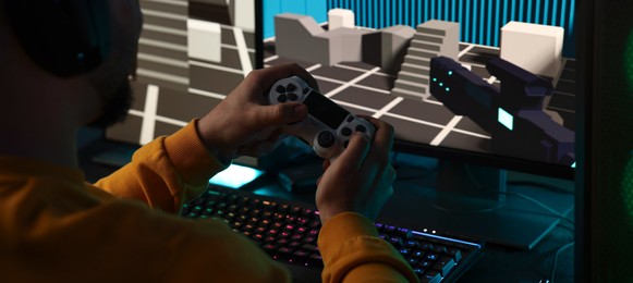 Photo of Man playing video games with controller at table indoors, closeup