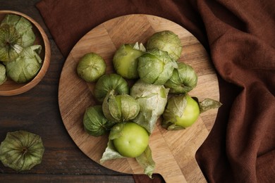 Photo of Fresh green tomatillos with husk on wooden table, flat lay