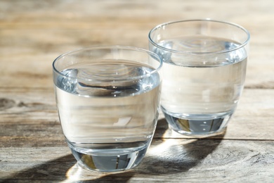 Photo of Glasses of water on wooden table. Refreshing drink