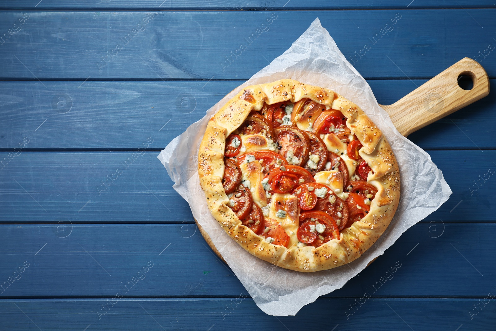 Photo of Tasty galette with tomato and cheese (Caprese galette) on blue wooden table, top view. Space for text