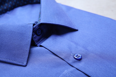 Photo of Closeup view of stylish blue shirt. Dry-cleaning service