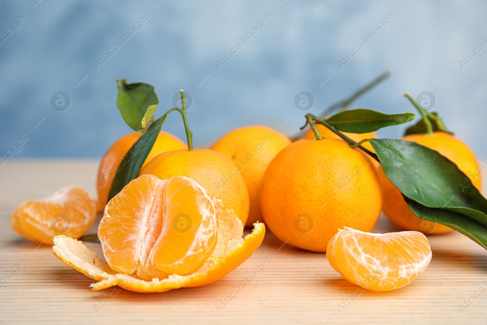 Photo of Fresh ripe tangerines with green leaves on table