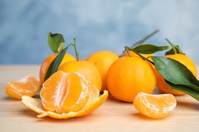 Fresh ripe tangerines with green leaves on table