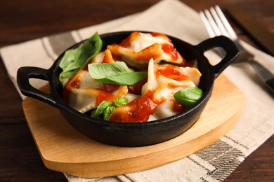 Tasty ravioli with tomato sauce served on wooden table