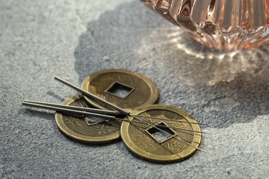 Acupuncture needles and Chinese coins on stone surface, closeup