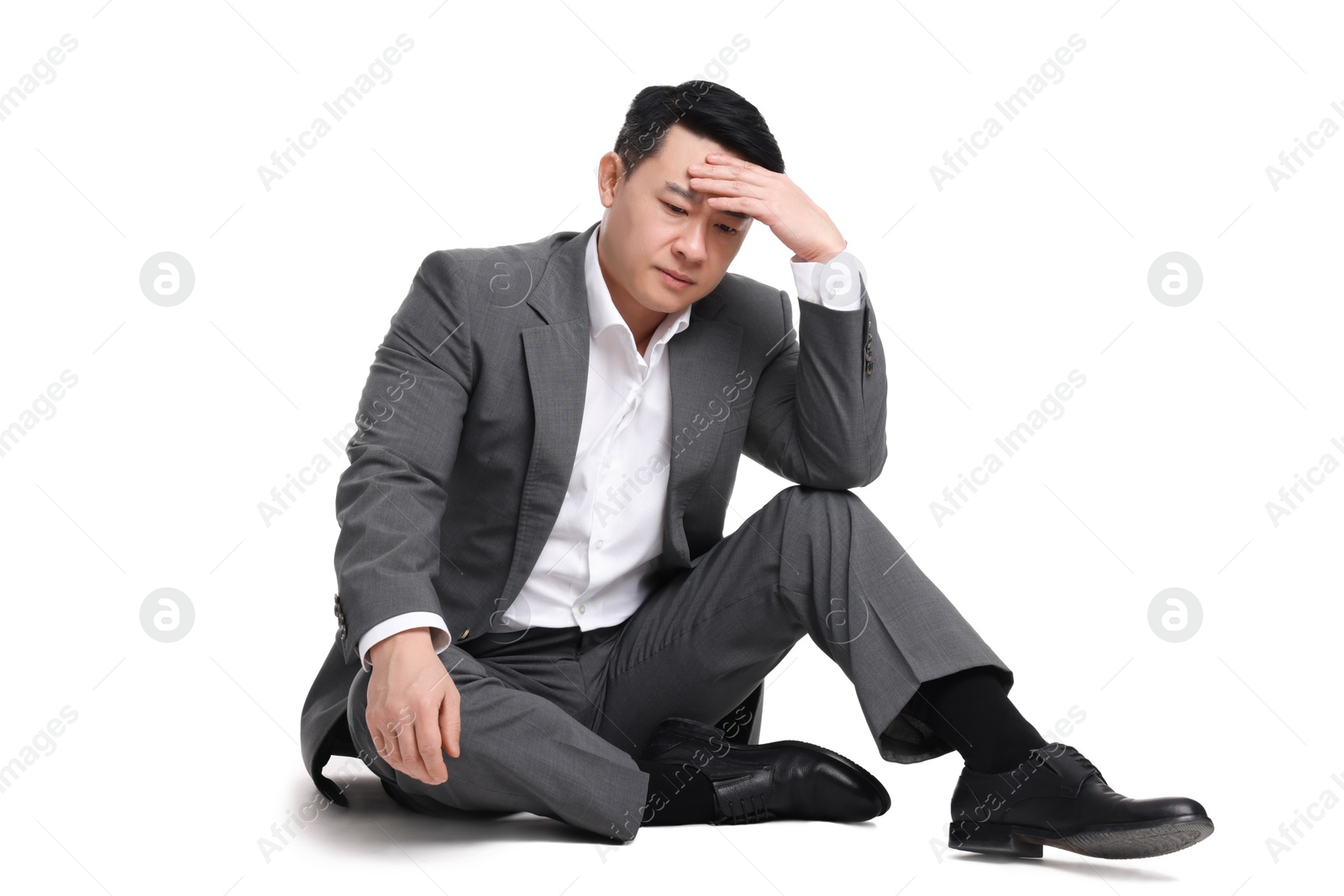 Photo of Tired businessman in suit sitting on white background