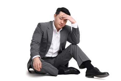 Photo of Tired businessman in suit sitting on white background