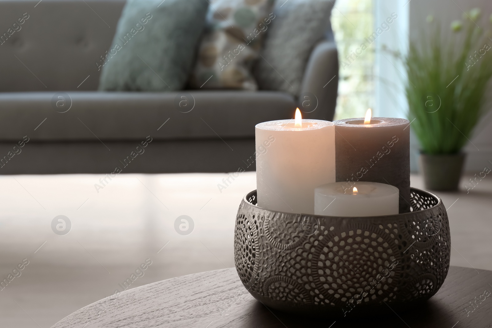 Photo of Vase with burning candles on table in living room