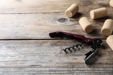 Photo of Opener with corkscrew and corks on wooden table, space for text