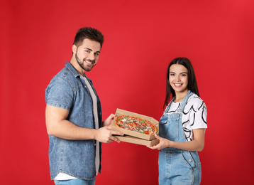 Happy young couple with pizza on red background