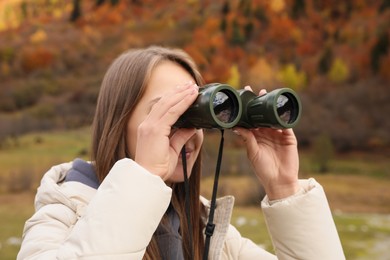 Woman looking through binoculars in beautiful mountains, closeup