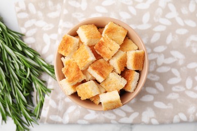 Delicious crispy croutons and rosemary on table, flat lay