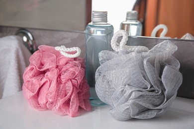 Colorful sponges between shower gel bottle on sink in bathroom, closeup