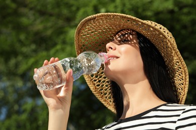 Photo of Beautiful young woman drinking water outdoors. Refreshing drink