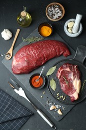 Photo of Pieces of raw beef meat and spices on black table, flat lay