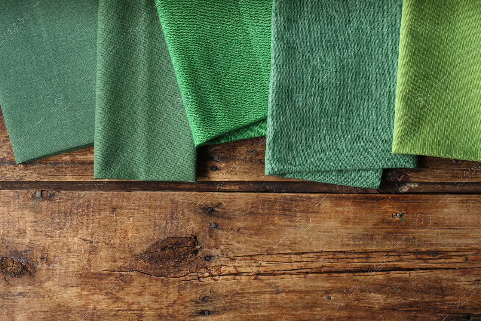 Photo of Different kitchen napkins on wooden table, flat lay. Space for text