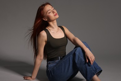 Photo of Beautiful young woman sitting on gray background