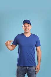 Photo of Happy man in cap and tshirt on light blue background. Mockup for design
