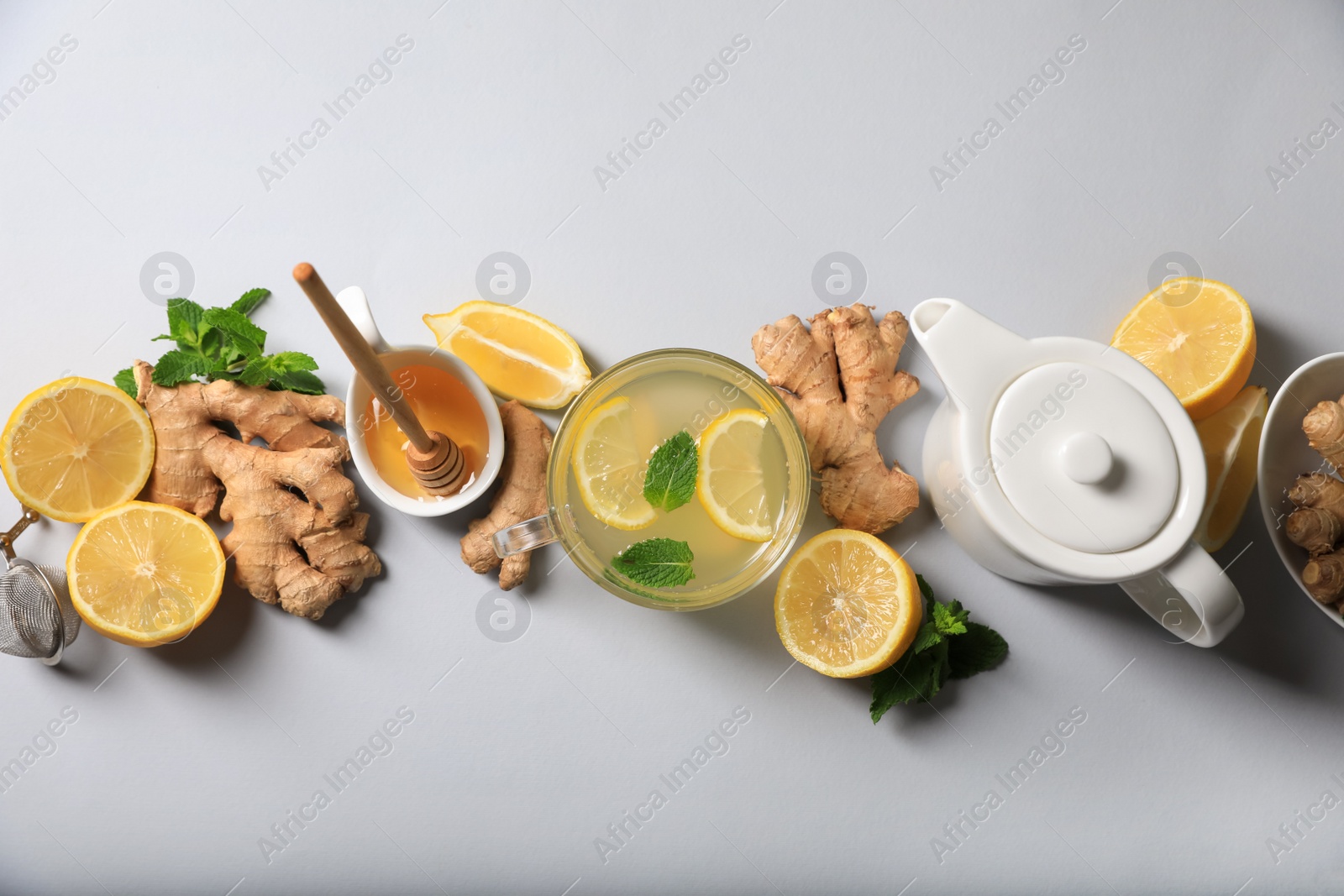 Photo of Delicious ginger tea and ingredients on light grey background, flat lay