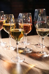 Different tasty wines in glasses on wooden table