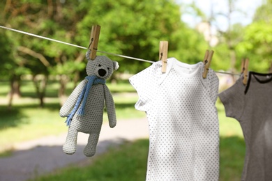 Photo of Baby onesies and toy bear hanging on clothes line outside