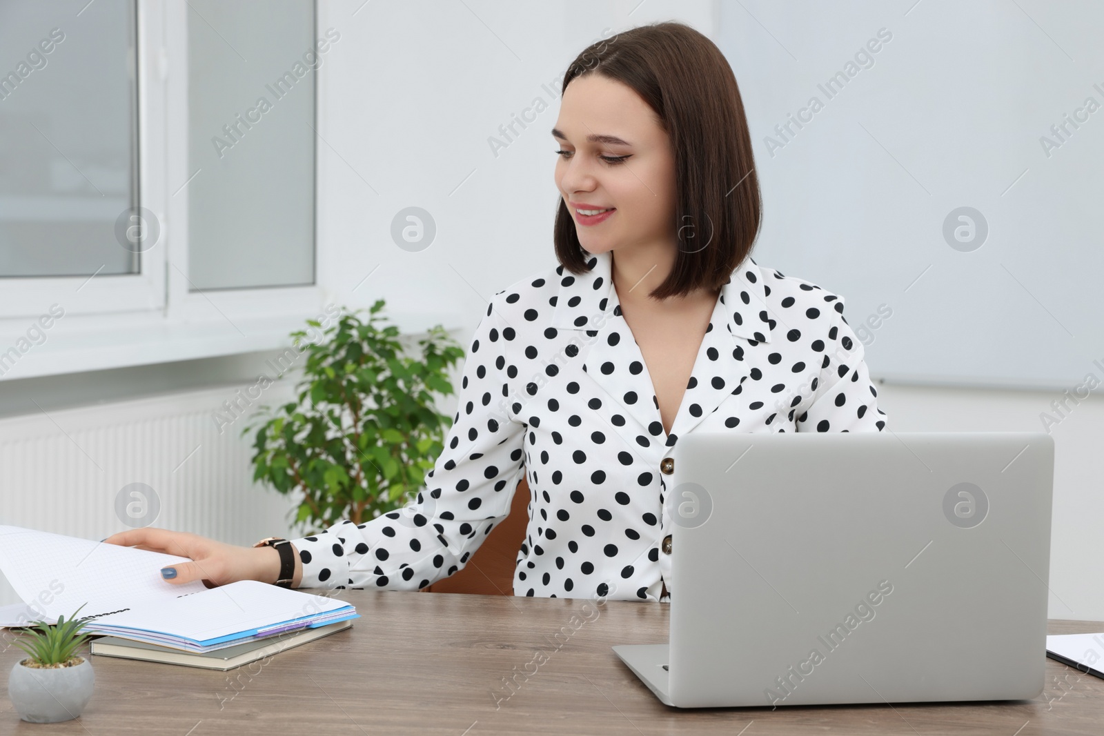 Photo of Happy young intern working at table in modern office