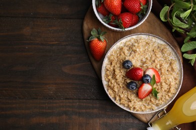 Photo of Tasty oatmeal with strawberries and blueberries in bowl on wooden table, flat lay. Space for text