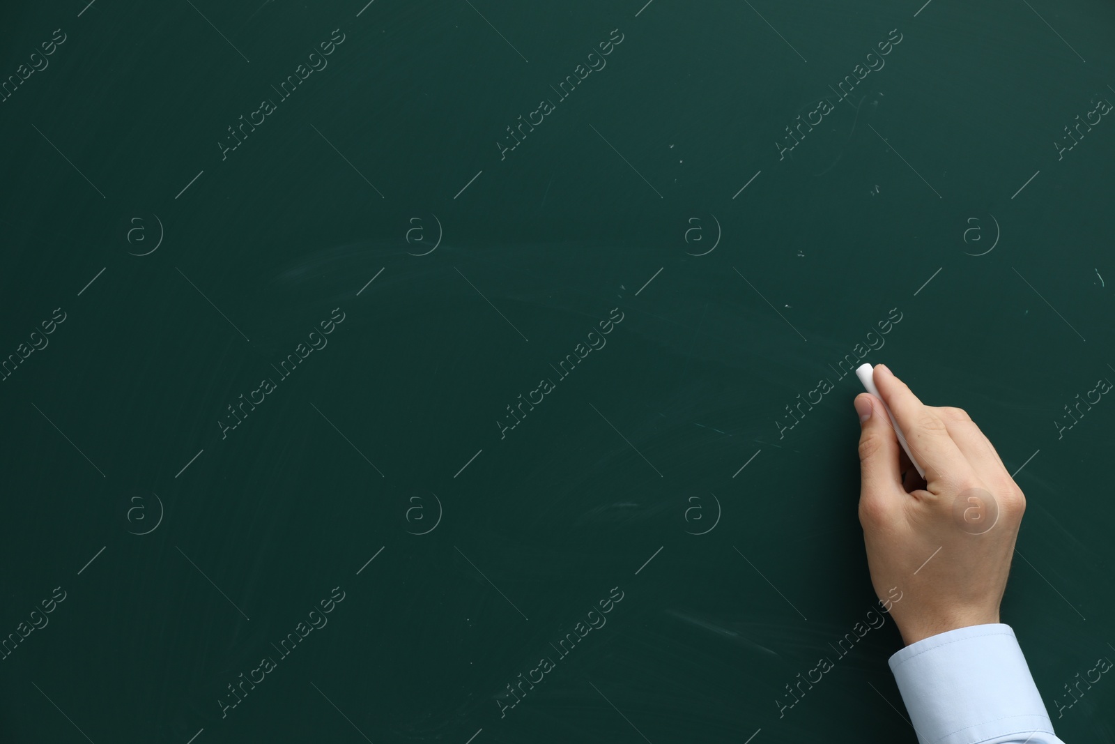 Photo of Teacher writing with chalk on green chalkboard, closeup. Space for text