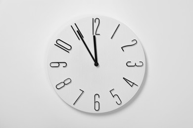 Stylish analog clock hanging on white wall. New Year countdown
