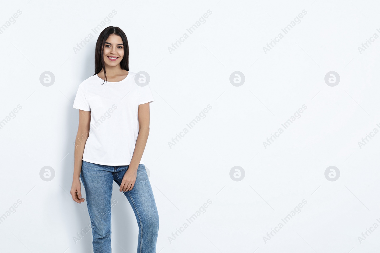 Photo of Young woman in stylish jeans on light background. Space for text