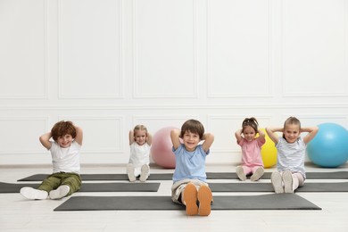 Photo of Group of children doing gymnastic exercises on mats indoors