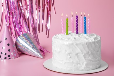 Photo of Delicious cake with burning candles and decorations on pink background. Space for text