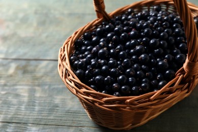 Photo of Ripe blackcurrants in wicker basket on wooden rustic table. Space for text