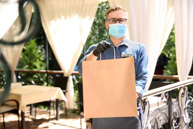 Photo of Waiter with packed takeout order in restaurant. Food service during coronavirus quarantine