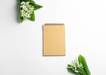 Notebook and lily of the valley bouquets on white background, flat lay. Space for text