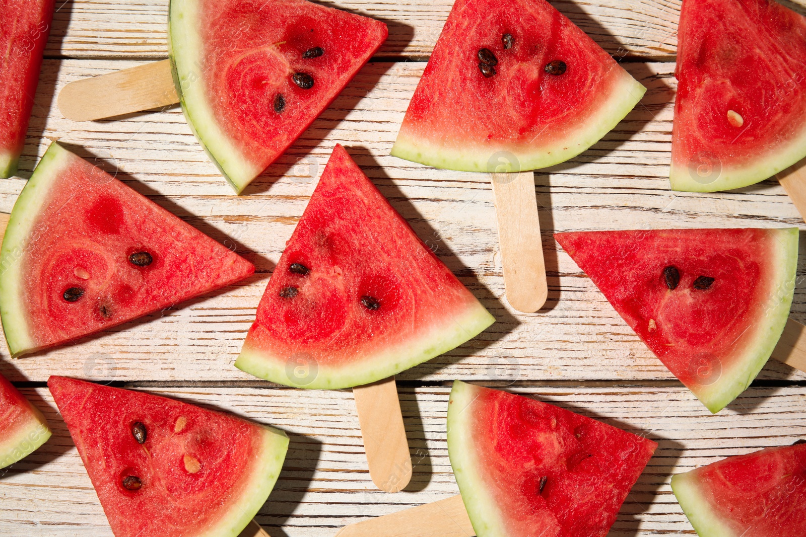 Photo of Slices of ripe watermelon on white wooden table, flat lay