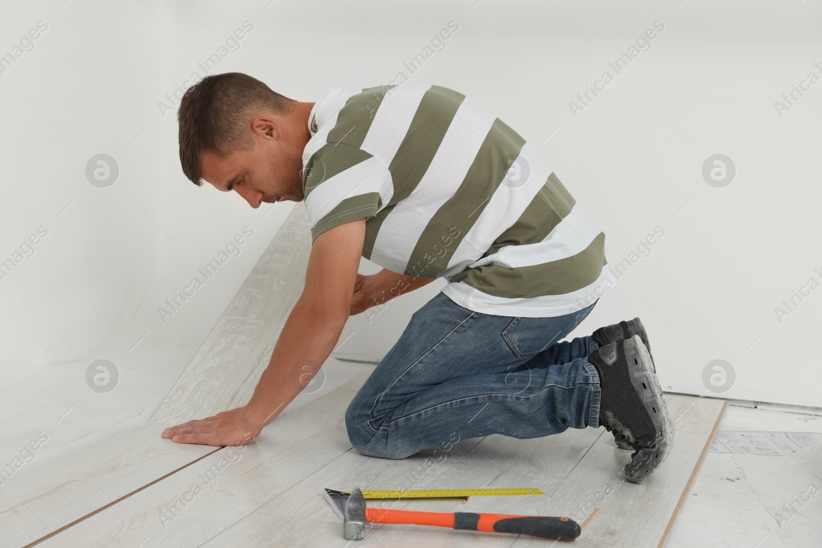 Photo of Professional worker installing new laminate flooring indoors