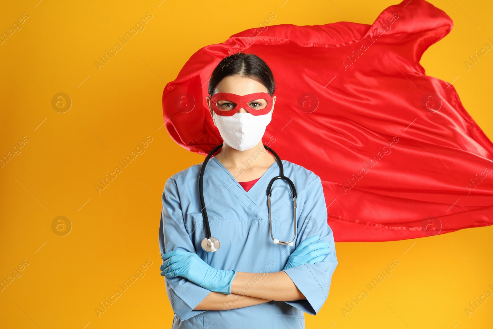 Photo of Doctor dressed as superhero posing on yellow background. Concept of medical workers fighting with COVID-19