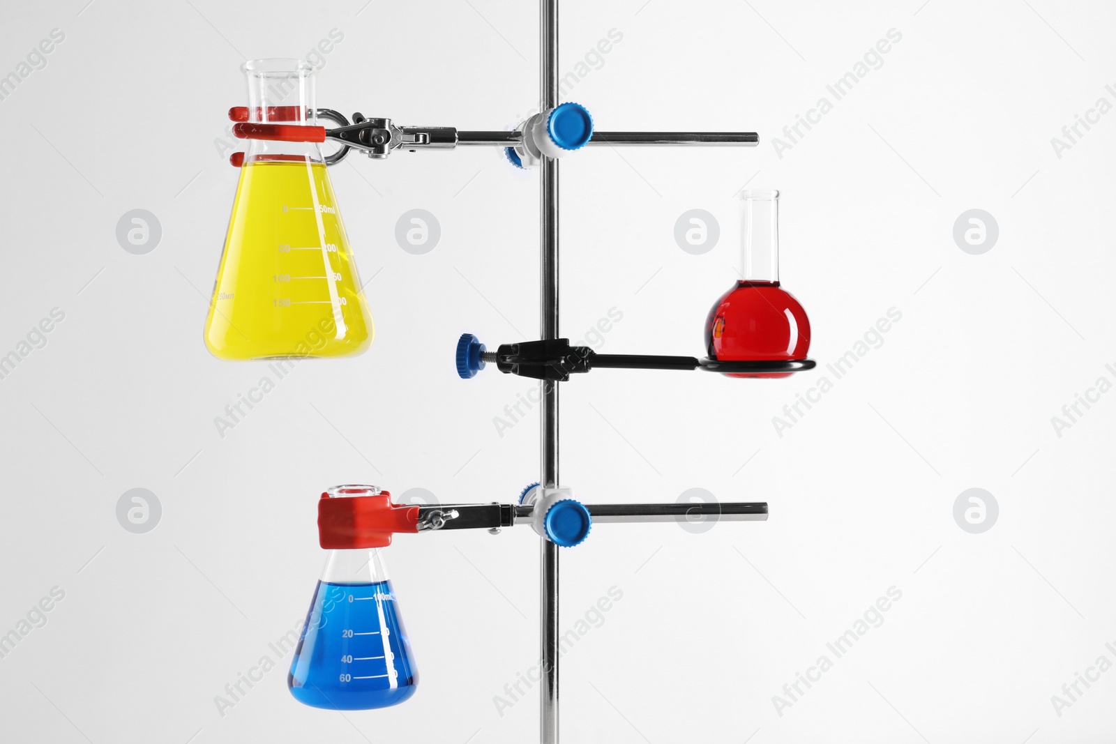 Photo of Retort stand and laboratory flasks with liquids on white background