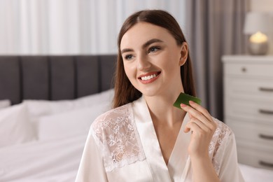 Photo of Young woman applying aloe gel from leaf onto her neck indoors