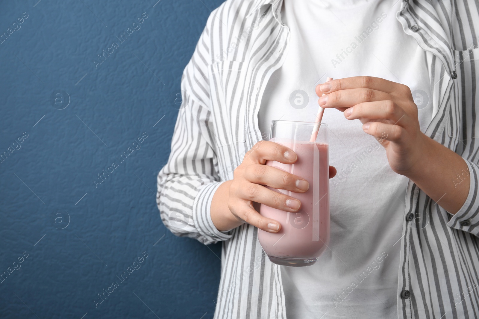 Image of Woman with glass of tasty smoothie on blue background, closeup