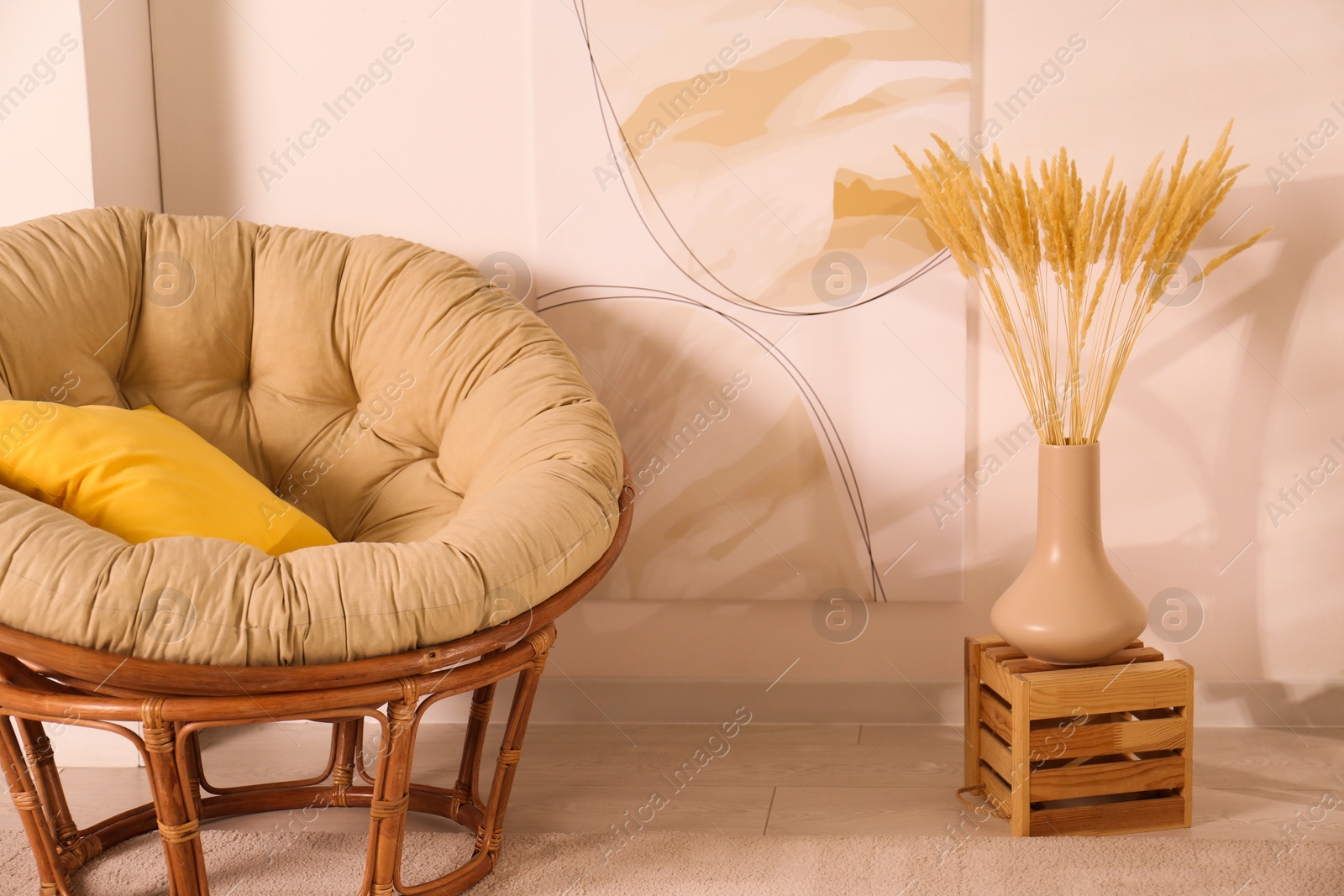 Photo of Vase with decorative dried plants and painting near papasan chair in stylish room interior