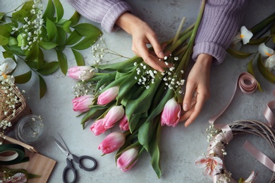 Female decorator creating beautiful bouquet at table