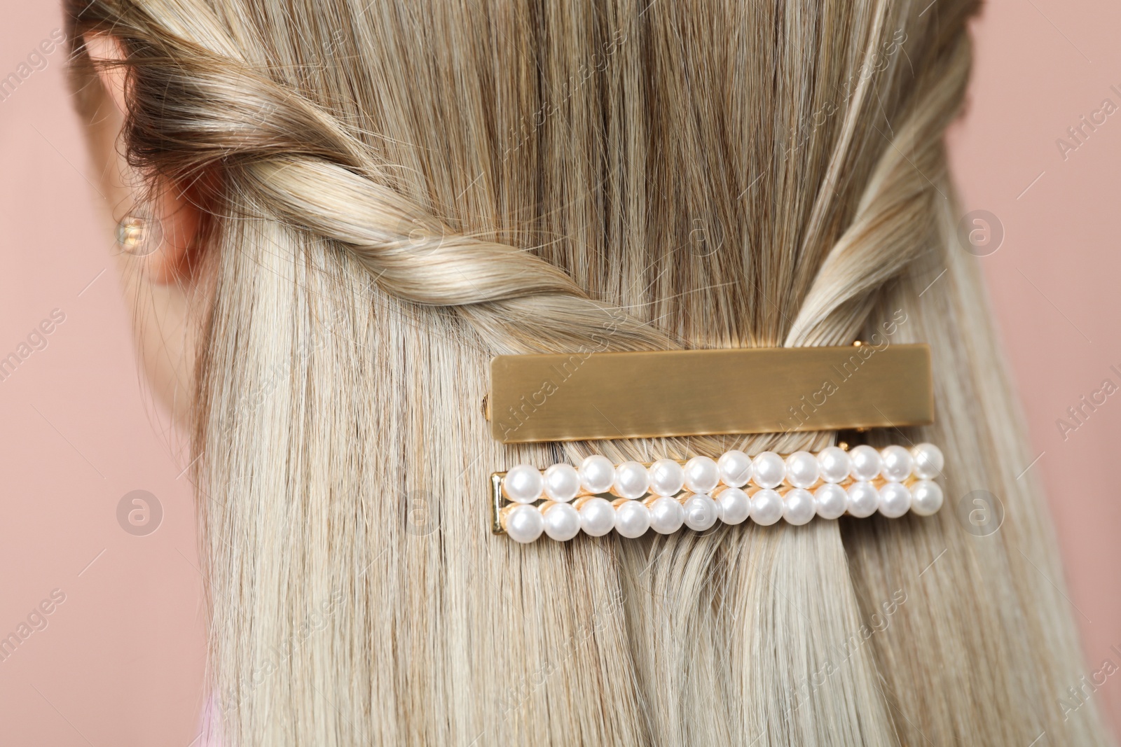 Photo of Young woman with beautiful gold hair clips on pink background, closeup