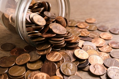 Photo of Glass jar with coins on table, closeup. Money saving concept